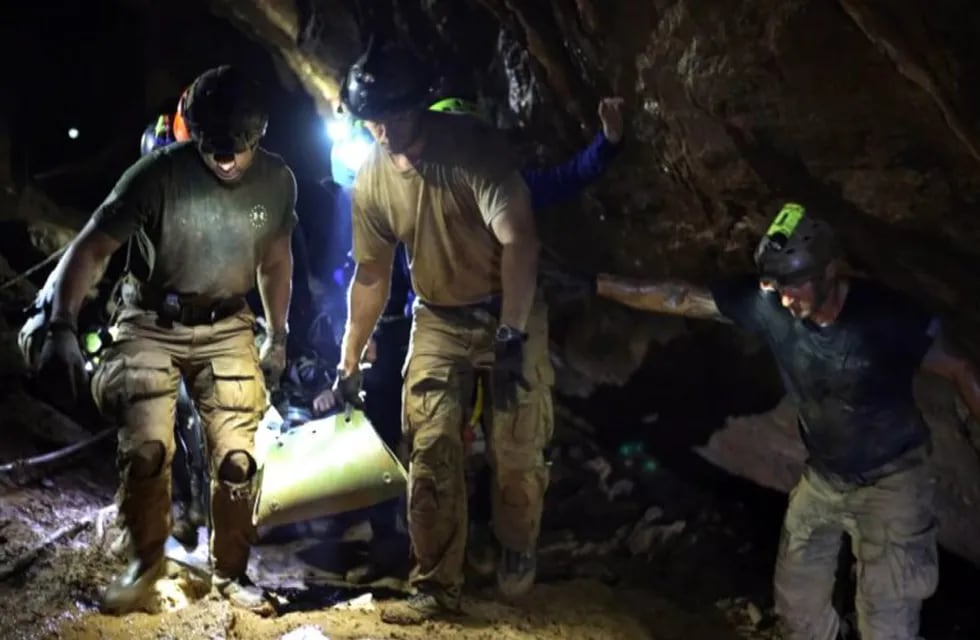 Varios miembros del equipo de rescate evacuan a un niño del equipo juvenil de fútbol atrapado en la cueva Tham Luang.