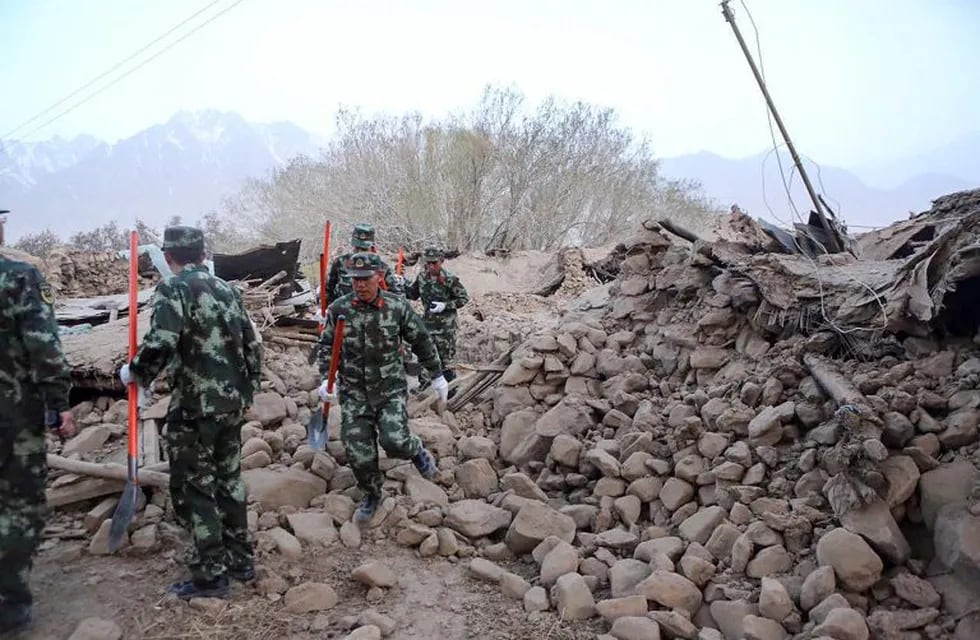 In this photo released by Xinhua News Agency, soldiers walk past damaged houses following an earthquake in Kuzigun Village in Taxkorgan County, northwest China's Xinjiang Uygur Autonomous Region, Thursday, May 11, 2017. A moderate earthquake that struck close to the earth’s surface killed at least several people, the region's earthquake administration said. (Li Jing/Xinhua via AP) china Taxkorgan  Ocho muertos y 23 heridos por terremoto en China desastres naturales terremotos