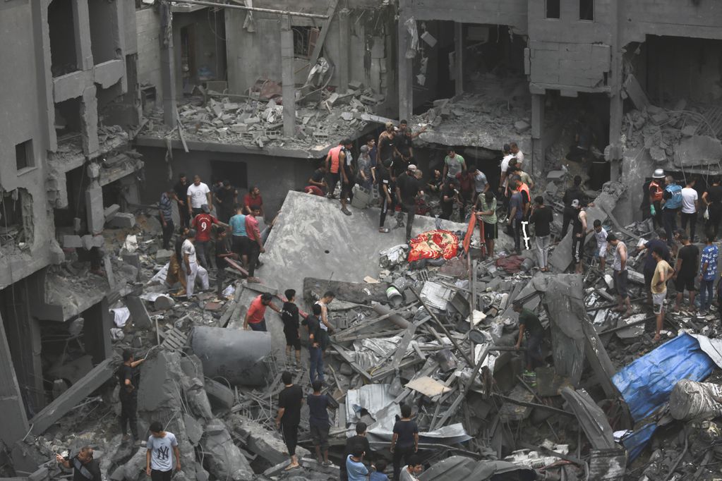 Palestinos inspeccionan los daños en edificios destruidos por ataques aéreos israelíes, en la Ciudad de Gaza, el 27 de octubre de 2023.