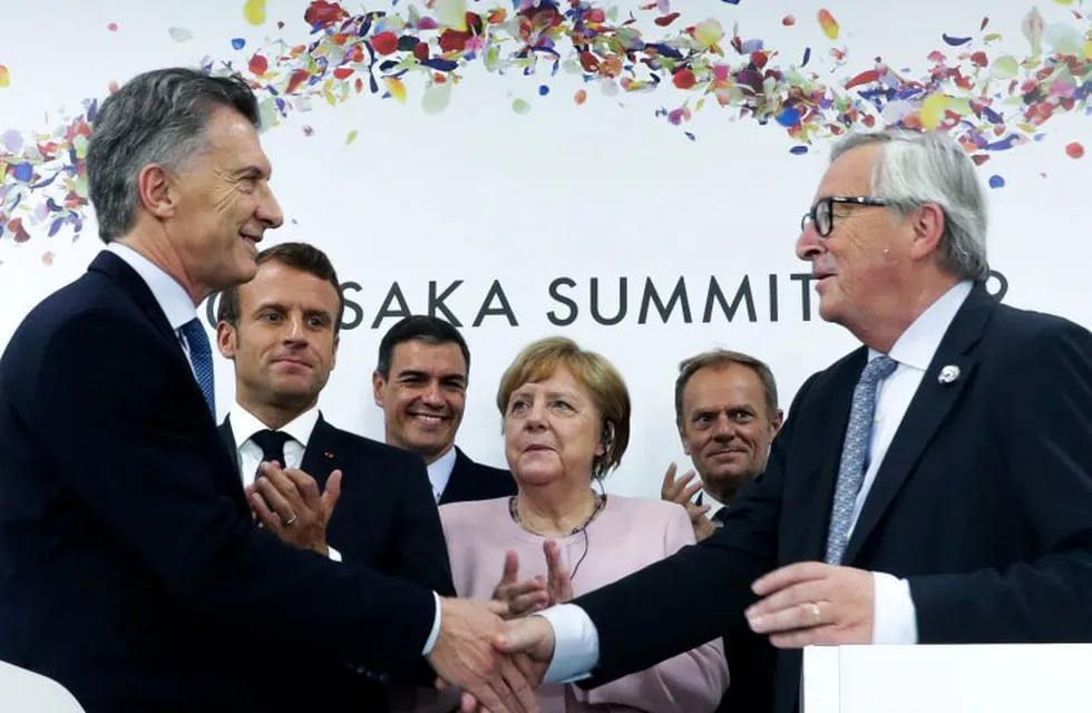 In this Handout released by Argentina's Presidency, Argentina's President Mauricio Macri ( L) and European Commission President Jean-Claude Juncker (R) greet eachother as France's President Emmanuel Macron (2-L), Spanish President Pedro Sanchez (3-L), German Chancellor Angela Merkel (C) and EU Council President Donald Tusk look on during a press conference at the G20 Osaka Summit in Osaka on June 29, 2019. - European farmers and environmentalists have denounced a historic trade deal signed between the EU and South American countries as a \