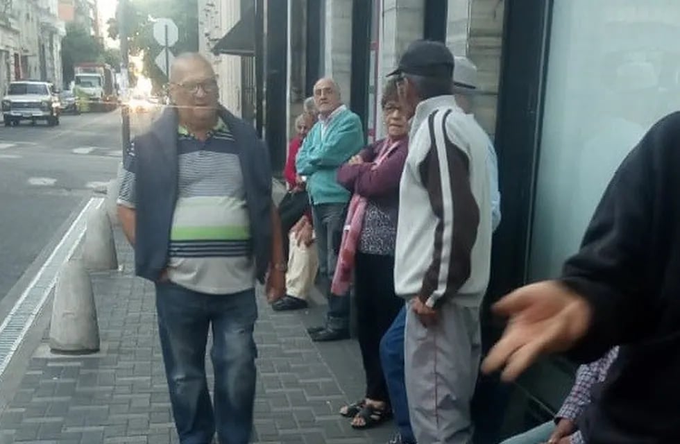 En la vereda de un banco en Sarmiento y San Lorenzo los jubilados igual hicieron fila para cobrar pese a que la entidad no abre en medio de la cuarentena total. (Radio 2)