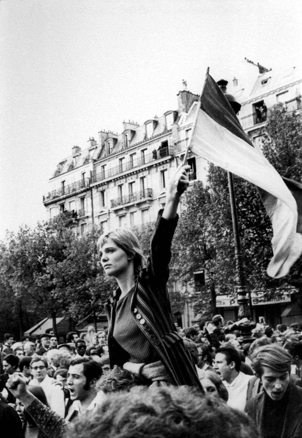 Caroline Brener era una inglesa de visita en París en esos días de mayo y asegura que se subió a los hombros de un amigo porque estaba cansada, que no sabía de qué era esa bandera y que alguien tomó la foto sin que ella  sospechara que luego se convertiría en la involuntaria “Marianne del mayo francés”.