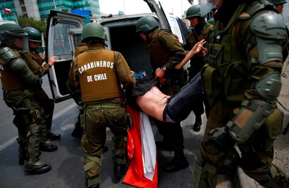 TOPSHOT - The police arrest a demonstrator during clashes between protesters and the police at Plaza de Maipu in Santiago, on October 19, 2019. - Chile's president declared a state of emergency in Santiago Friday night and gave the military responsibility for security after a day of violent protests over an increase in the price of metro tickets. (Photo by Pablo VERA / AFP)