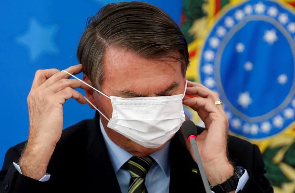 FILE PHOTO: Brazil's Jair Bolsonaro adjusts his protective face mask during a news conference to announce measures to curb the spread of the coronavirus disease (COVID-19) in Brasilia, Brazil March 18, 2020. REUTERS/Adriano Machado/File Photo