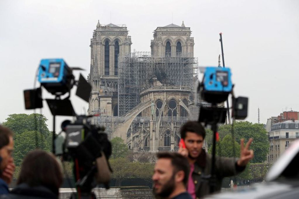 Members of the media work on a bridge after a massive fire devastated large parts of Notre-Dame Cathedral in Paris, France April 16, 2019. REUTERS/Yves Herman