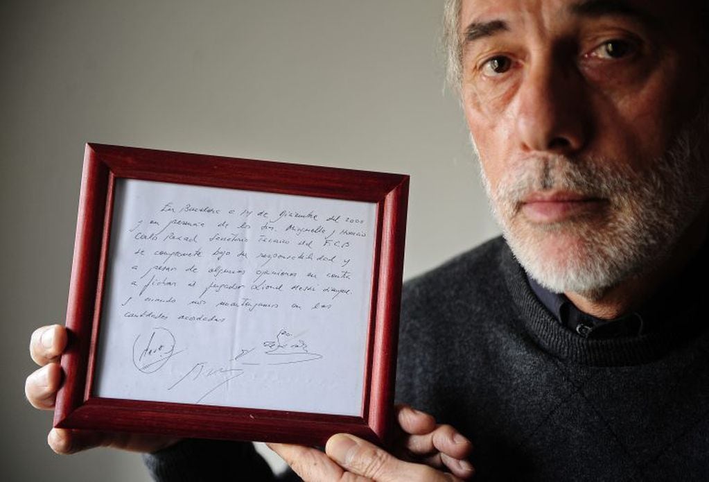 In this photo taken, Thursday, Jan. 5, 2012, Horacio Gaggioli holds a framed copy of the napkin linking a 13-year-old Lionel Messi to FC Barcelona in Barcelona, Spain. Gaggioli had been asked by contacts from Messi's hometown of Rosario,Argentina, to help broker a tryout with Barcelona because the family had decided to leave Newell's Old Boys for the football riches of Europe. The small napkin reads: "In Barcelona, on the 14th of December of 2000 and in the presence of Josep Minguella and Horacio (Gaggioli), Carles Rexach, F.C.B technical secretary, it commits under his responsibility and despite some views against it to sign the player Lionel Messi, as long we stick to amounts agreed upon."(AP Photo/Manu Fernandez)