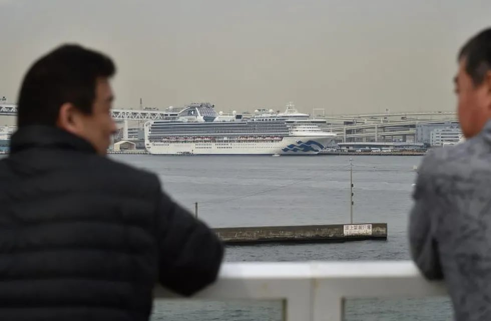 CORRECTION - The Diamond Princess cruise ship (back) in quarantine due to fears of the new COVID-19 coronavirus, is seen at the Daikoku Pier Cruise Terminal in Yokohama on February 20, 2020. - Two former passengers of the coronavirus-wracked Diamond Princess have died, local media reported, as fears mount about those who have left the ship after testing negative for the virus. (Photo by Kazuhiro NOGI / AFP) / “The erroneous mention[s] appearing in the metadata of this photo by Kazuhiro NOGI has been modified in AFP systems in the following manner: changes country in object name slug in metadata [JAPAN] instead of [HONG KONG]. Please immediately remove the erroneous mention[s] from all your online services and delete it (them) from your servers. If you have been authorized by AFP to distribute it (them) to third parties, please ensure that the same actions are carried out by them. Failure to promptly comply with these instructions will entail liability on your part for any continued or