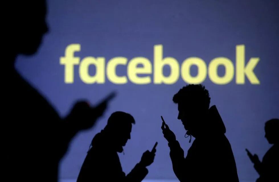 FILE PHOTO: Silhouettes of mobile users are seen next to a screen projection of the Facebook logo in this picture illustration taken March 28, 2018.  REUTERS/Dado Ruvic/Illustration/File Photo