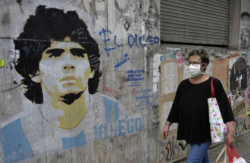 A woman walks by a graffiti depicting Argentine former football star Diego Maradona during the lockdown imposed by the government against the spread of the new coronavirus, COVID-19, in Buenos Aires, Argentina, on April 22, 2020. (Photo by JUAN MABROMATA / AFP)