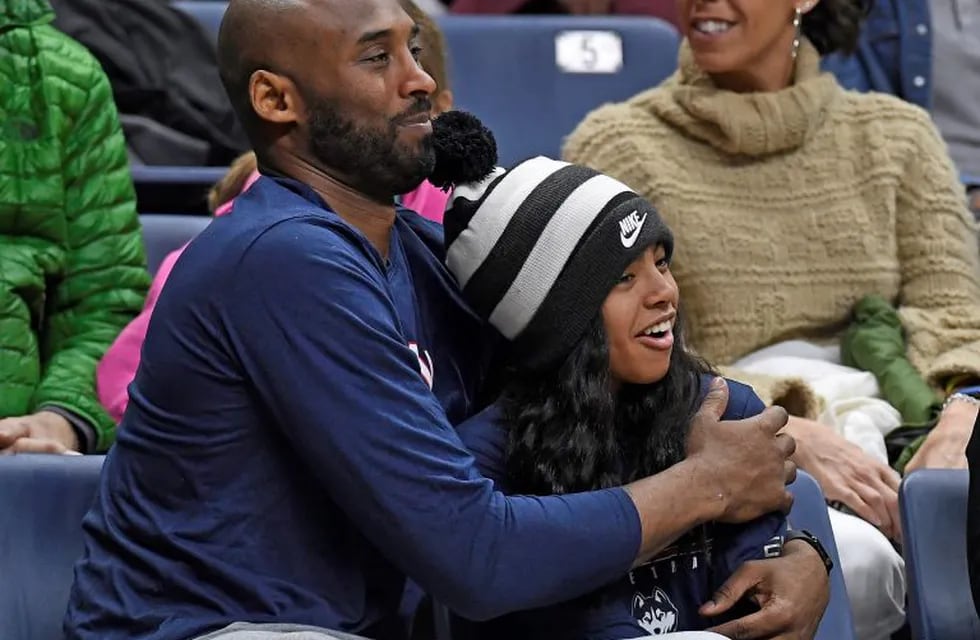 FILE - In this March 2, 2019, file photo, Kobe Bryant and his daughter Gianna watch the first half of an NCAA college basketball game between Connecticut and Houston in Storrs, Conn. Autopsy reports released Friday, May 15, 2020, show that the pilot who flew Bryant show he did not have drugs or alcohol in his system when the helicopter crashed in Southern California in January, killing all nine aboard. The causes of death for Bryant, his 13-year-old daughter Gianna, pilot Ara Zobayan and the others have been ruled blunt force trauma. Federal authorities are still investigating the Jan. 26 incident where the chopper crashed into the Calabasas hillsides. (AP Photo/Jessica Hill, File)