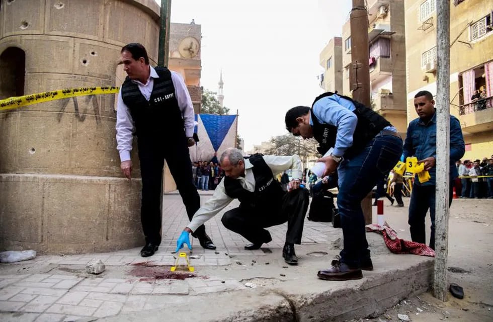 Egyptian security members and forensic police inspect the site of a gun attack outside a church south of the capital Cairo, on December 29, 2017.\nA gunman opened fire on a church, killing at least nine people before policemen shot him dead, state media and officials said.  / AFP PHOTO / Samer ABDALLAH