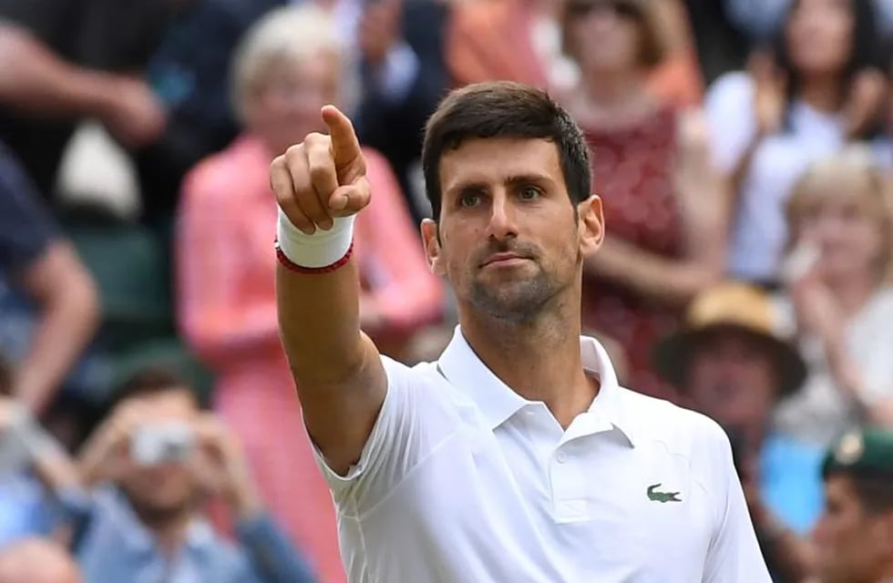 Serbia's Novak Djokovic celebrates beating Switzerland's Roger Federer during their men's singles final on day thirteen of the 2019 Wimbledon Championships at The All England Lawn Tennis Club in Wimbledon, southwest London, on July 14, 2019. (Photo by Ben STANSALL / AFP) / RESTRICTED TO EDITORIAL USE
