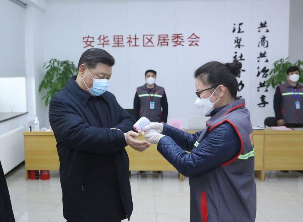Xi Jinping visita un centro de salud, usando un barbijo, y una enfermera le toma la temperatura (JU PENG / XINHUA / AFP)
