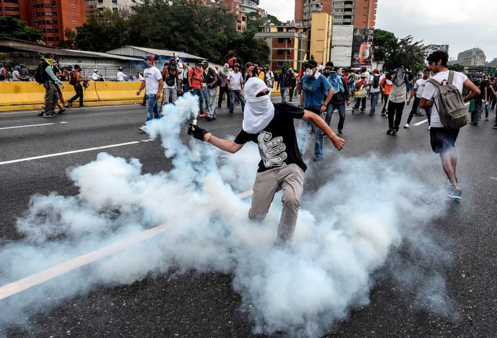 TOPSHOT - Demonstrators clash with the riot police during a protest against Venezuelan President Nicolas Maduro, in Caracas on April 20, 2017.
Venezuelan riot police fired tear gas Thursday at groups of protesters seeking to oust President Nicolas Maduro,