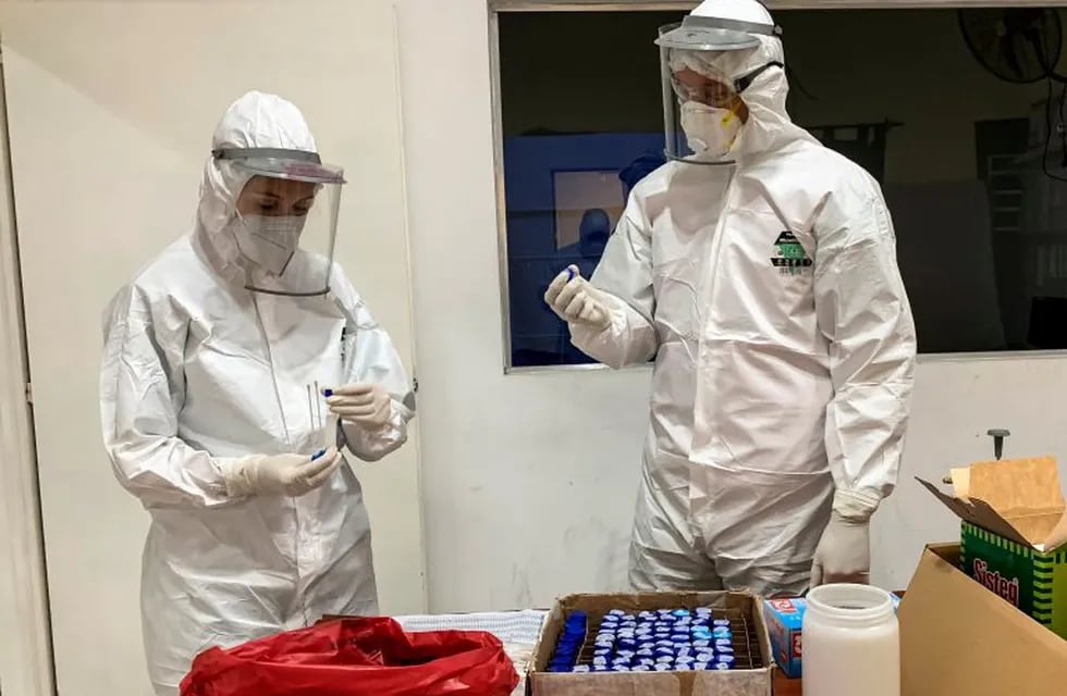 Argentine doctor Jhonny Escalante (R) and his colleague Mariana Castro prepare for swabbing to test for the COVID-19 coronavirus in a shelter for vulnerable people in Buenos Aires, on May 21, 2020. - The number of COVID-19 cases in Argentina has raised to more than 9.000, while the mandatory quarantine imposed on March 20 is still fully applied in the capital Buenos Aires. (Photo by RONALDO SCHEMIDT / AFP) coronavirus test casos del dia  laboratorio  testeos  PCR HISOPADO  ambulancia