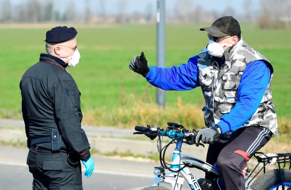 An Italian Carabinieri talk with a person in car at a police check-point few kilometers from the small town of Castiglione d'Adda, southeast of Milan, on February 24, 2020. - Under the shadow of a new coronavirus outbreak, Italy took drastic containment steps as worldwide fears over the epidemic spiralled. (Photo by Miguel MEDINA / AFP)