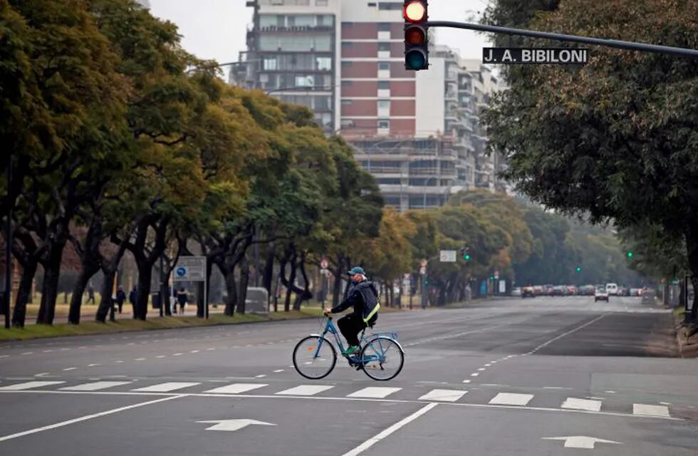 A man crosses an avenue on his bicycle in Buenos Aires on July 18, 2020 a day after Argentina's government announced it was relaxing coronavirus containment measures in the capital to fight the COVID-19 pandemic. - From Monday, non-essential businesses, industry and certain professional activities can restart and citizens will also be allowed to go outside for sport and to visit places of worship. (Photo by Alejandro PAGNI / AFP)