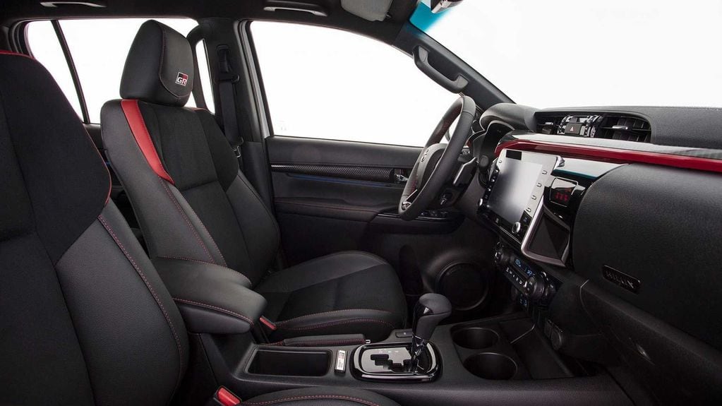 Tapizado de cuero natural y ecológico, combinado con Suede sintético perforado y detalles en rojo. Un interior tan deportivo como distinguido para la nueva Toyota Hilux GR-Sport III.