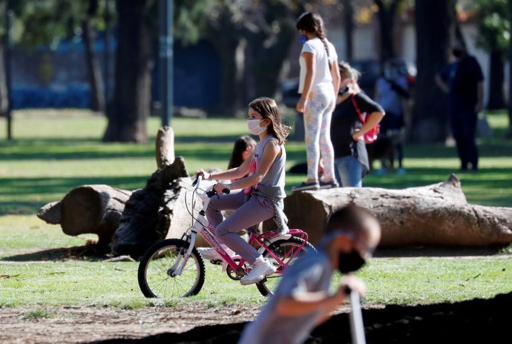 A girl wearing a face mask rides a bike in a park after restrictions were partially lifted for children in the city of Buenos Aires during the coronavirus disease (COVID-19) outbreak, Argentina May 16, 2020\u002E REUTERS/Agustin Marcarian