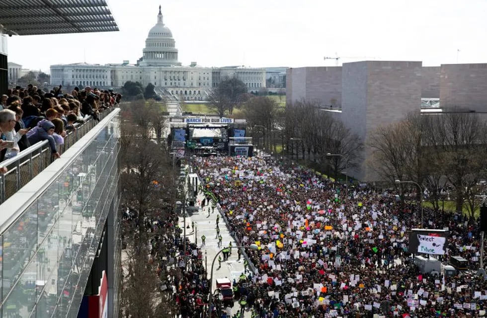 MRX16. Washington (United States), 24/03/2018.- Visitors (L) at the Newseum look out upon thousands of people gathered for March For Our Lives on Pennsylvania Avenue in Washington, DC, USA, 24 March 2018. March For Our Lives was organized in response to the 14 February shooting at Marjory Stoneman Douglas High School in Parkland, Florida. The student activists demand that their lives and safety become a priority, and an end to gun violence and mass shootings in schools. (Estados Unidos) EFE/EPA/MICHAEL REYNOLDS