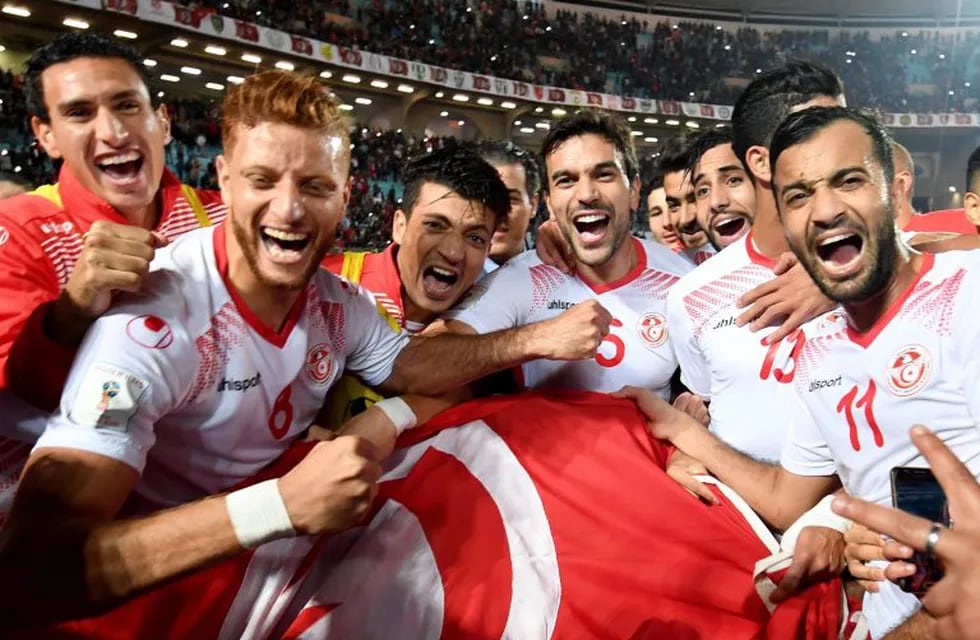 Players of the Tunisian national football team celebrate with their national flag after qualifying for the 2018 World Cup finals after winning their qualifiers match against Libya at the Rades Olympic Stadium in the capital Tunis on November 11, 2017. / AFP PHOTO / FETHI BELAID