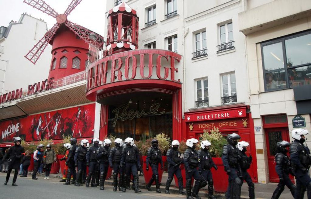 Los agentes de policía pasan junto al cabaret Moulin Rouge mientras aseguran una manifestación para conmemorar el primer aniversario del movimiento de los "chalecos amarillos" en París. Crédito: REUTERS / Charles Platiau.