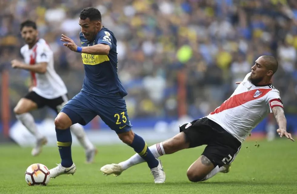 Boca Juniors' Carlos Tevez (L) drives the ball past River Plate's Jonatan Maidana during the first leg match of their all-Argentine Copa Libertadores final, at La Bombonera stadium in Buenos Aires, on November 11, 2018. (Photo by Eitan ABRAMOVICH / AFP) cancha boca juniors carlos tevez futbol copa libertadores 2018 partido final futbol copa libertadores primer partido final futbolistas boca juniors river plate