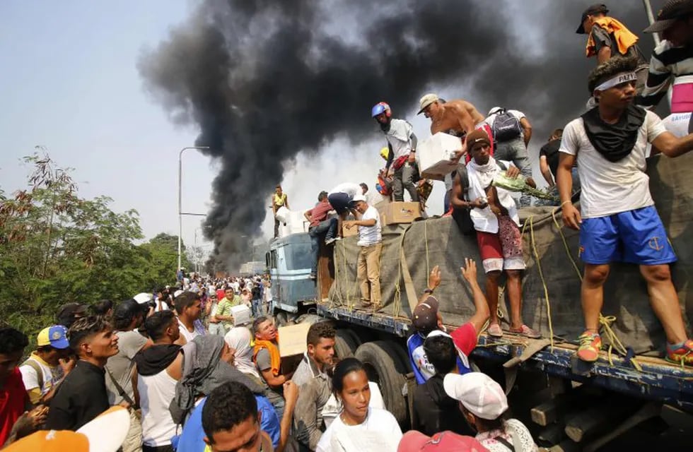 TOPSHOT - People try to salvage humaitarian aid after the truck carrying it was set ablaze on the Francisco de Paula Santander International Brige between Cucuta in Colombia and Ureña in Venezuela, on February 23, 2019. - A truck loaded with humanitarian aid was set ablaze on Saturday on the Colombia-Venezuela border, an opposition deputy told reporters amid rioting on the Santander bridge crossing. (Photo by Schneyder Mendoza / AFP)