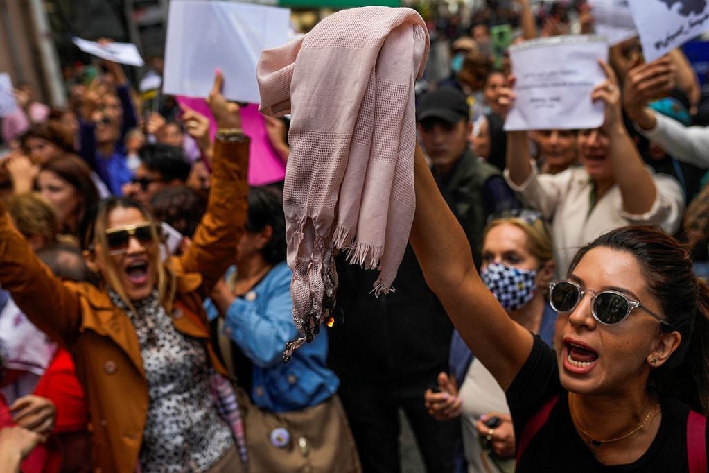 Una mujer quema un velo, o hiyab, mientras grita consignas con otras personas durante una protesta contra la muerte de la iraní Mahsa Amini. Foto: AP.