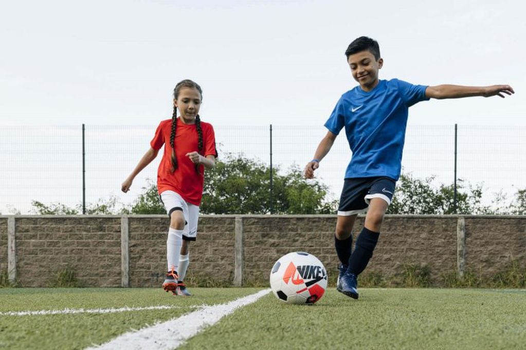 Niño y niña jugando al fútbol- imagen ilustrativa.