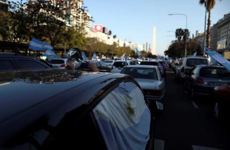 A demonstrator hits a pot lid with a spoon inside a car as she takes part in a protest against Argentina's national government amid the coronavirus disease (COVID-19) outbreak, at the Buenos Aires obelisk, Argentina September 13, 2020. REUTERS/Agustin Marcarian