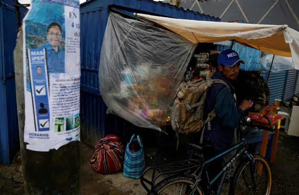 A man holds a bike next to an election poster of presidential candidate Luis Arce of Movement to Socialism party (MAS) in El Alto, on the outskirts of La Paz, Bolivia October 17, 2020. REUTERS/David Mercado