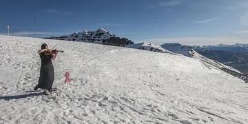 Tania Rubiolo tocando el violín en el cerro Teta para concientizar sobre el cáncer de mama.