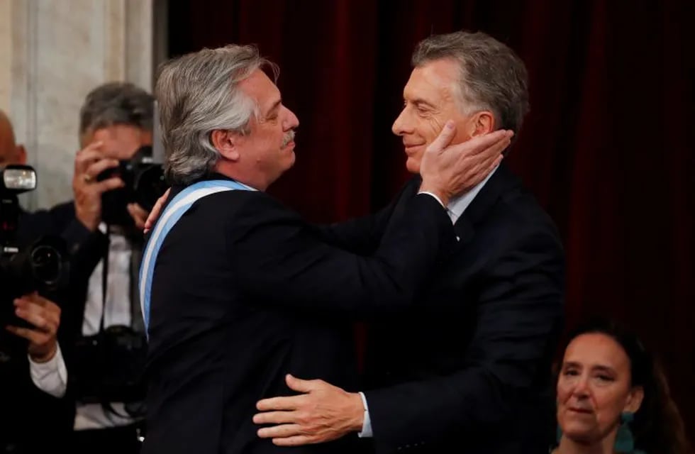 In this Dec. 10, 2019 photo, Argentina's new President Alberto Fernandez, left, embraces outgoing president Mauricio Macri after taking the oath of office at the Congress in Buenos Aires, Argentina. (AP Photo/Natacha Pisarenko)
