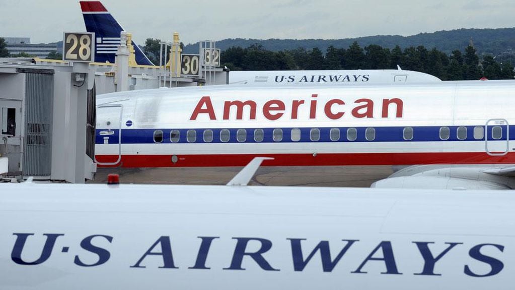 AVIÓN. De American Airlines se ve entre dos aeronaves de US Airways, este martes en el aeropuerto de Washington Nacional Ronald Reagan (AP).