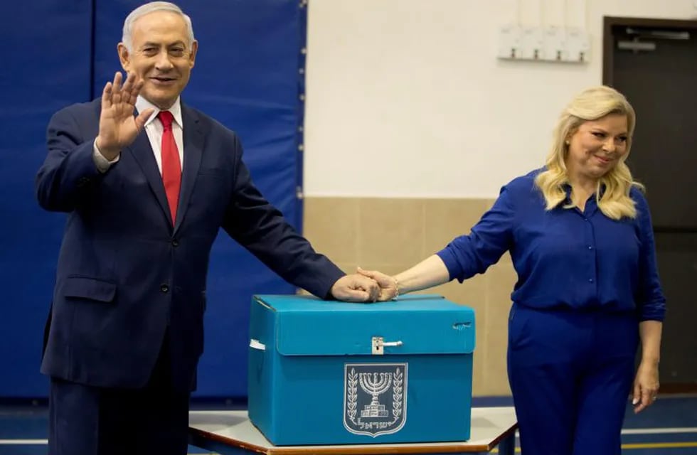 El primer ministro de Israel, Benjamin Netanyah, saluda junto a su mujer Sara, tras votar en las elecciones parlamentarias del país, en Jerusalén