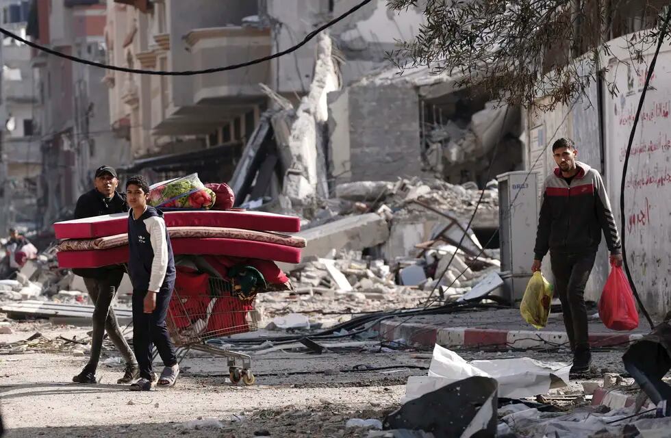 Palestinos caminan por zonas destrozadas por bombardeos israelíes en el campo de refugiados de Nusseirat, en la Franja de Gaza, el martes 16 de enero de 2024.
