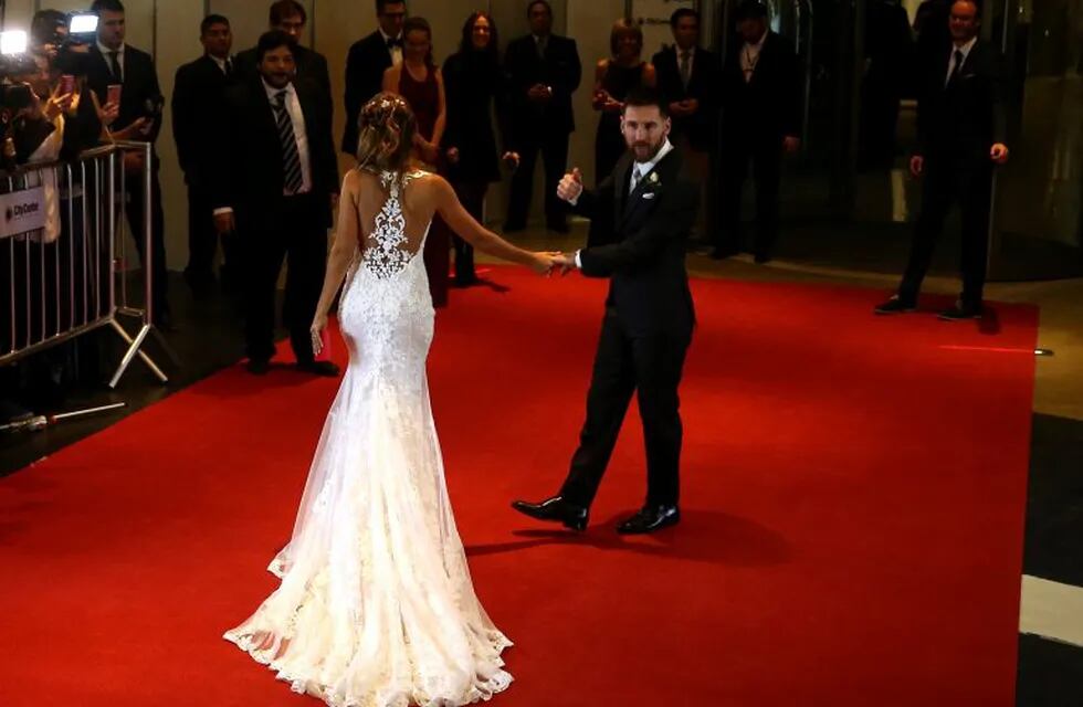 Argentine soccer player Lionel Messi and Antonela Roccuzzo pose as two women hold her dress at their wedding in Rosario, Argentina, June 30, 2017. REUTERS/Marcos Brindicci