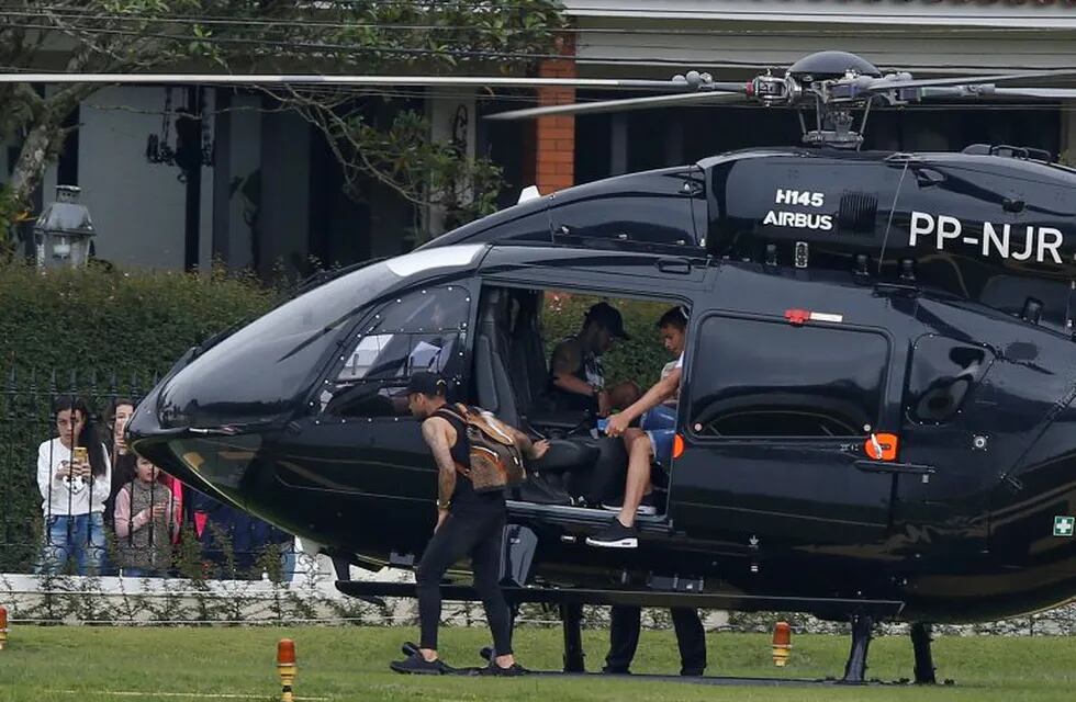 Brazil's soccer player Neymar sits inside his helicopter as teammates Thiago Silva, right, and Daniel Alves, left, exit as they arrive to the Granja Comary training center to train for the Copa America tournament in Teresopolis, Brazil, Sunday, June 2, 2019. A Brazilian police document says an unidentified woman has accused soccer star Neymar of raping her in Paris last month. After the revelation, the player used Instagram to publish a 7-minute video that includes WhatsApp messages he says he exchanged with the accuser in a friendly way days later. (AP Photo/Leo Correa)