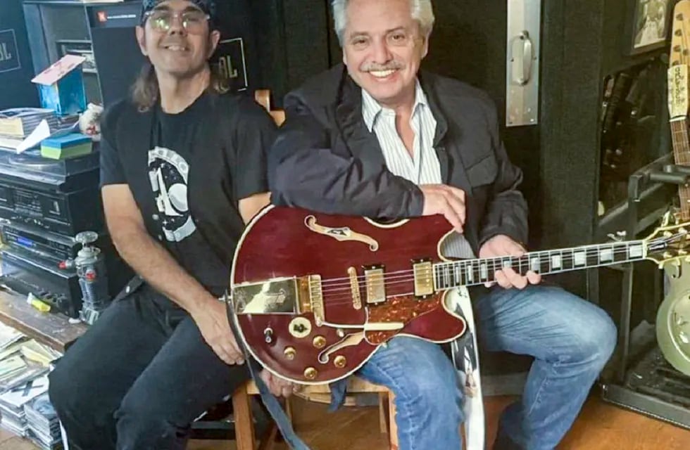 Alberto Fernández probando una guitarra junto a un músico de David Bowie