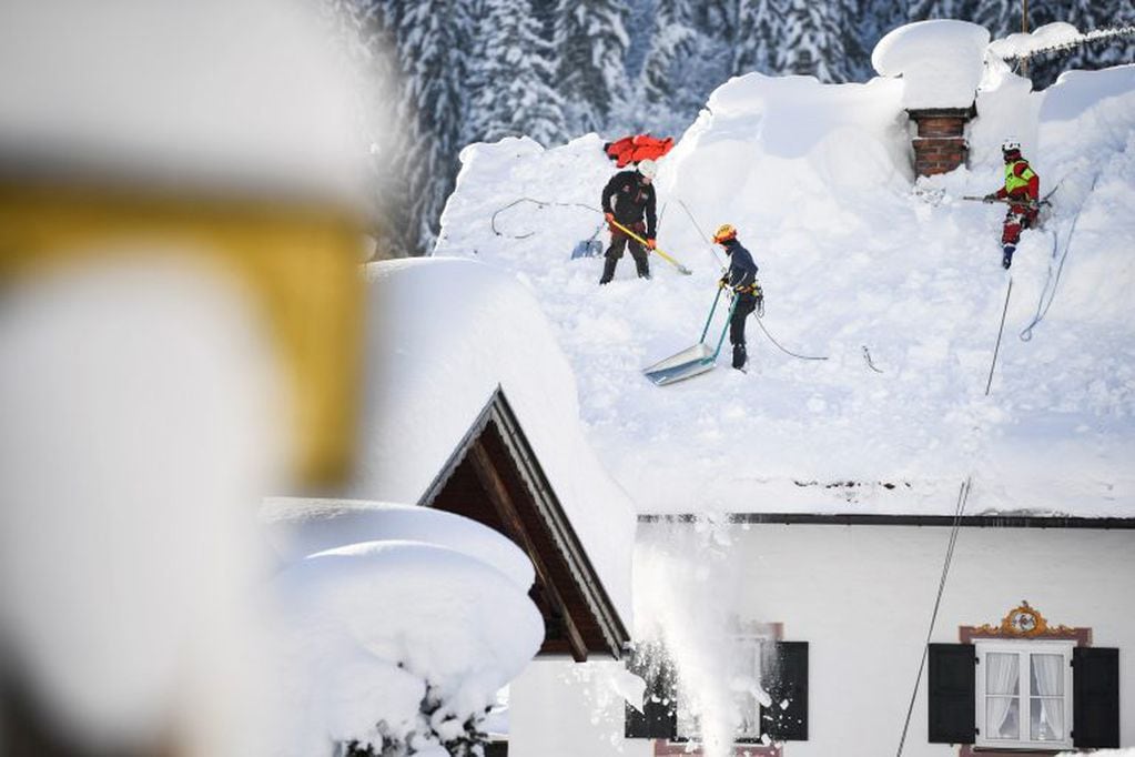 Operarios retiran la nieve de un tejado en Gerold, Alemania. Las persistentes nevadas registradas en Múnich y en Fráncfort obligaron hoy a cancelar unos 200 vuelos. Crédito: EFE/ Philipp Guelland.