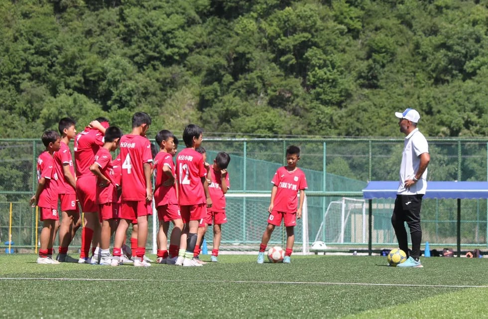 Nahuel Oyola hablando con sus pequeños dirigidos en el entrenamiento en su escuela de fútbol en China