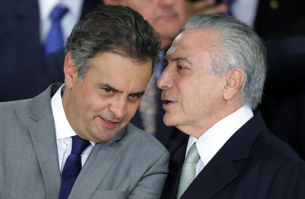 FILE - In this May 12, 2016 file photo, Brazil's acting President Michel Temer whispers into the ear of Sen. Aecio Neves, at Planalto presidential palace in Brasilia, Brazil. On Thursday, May 18, 2017, Brazilian federal police searched the office and homes of Neves, a top senator and presidential contender. He is being investigated in several corruption cases related to the \