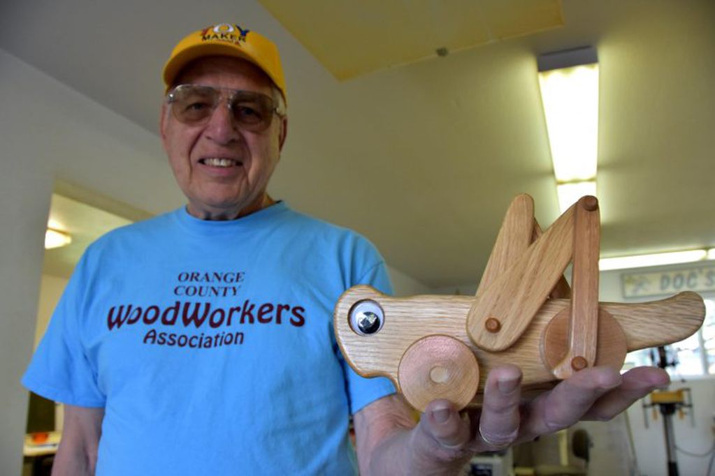 El miembro de la organización no lucrativa Orange County Woodworkers de California, Bill Rogers, de 82 años, posa mostrando un juguete de madera este 18 de diciembre de 2018 en el taller de carpintería en la casa de Ken Crandall en Anaheim (EFE/Iván Mejía)