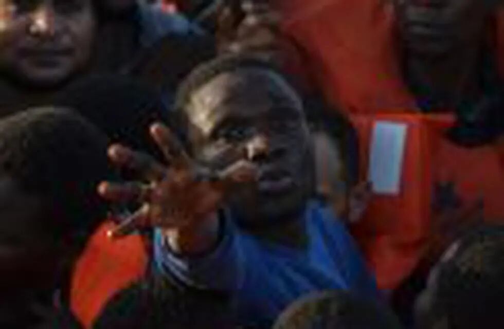 TOPSHOT - Migrants and refugees seated on a rubber boat grab life jackets thrown by members of the crew of the Topaz Responder rescue ship run by Maltese NGO Moas and Italian Red Cross, off the Libyan coast in the  Mediterranean Sea, on November 3, 2016. 