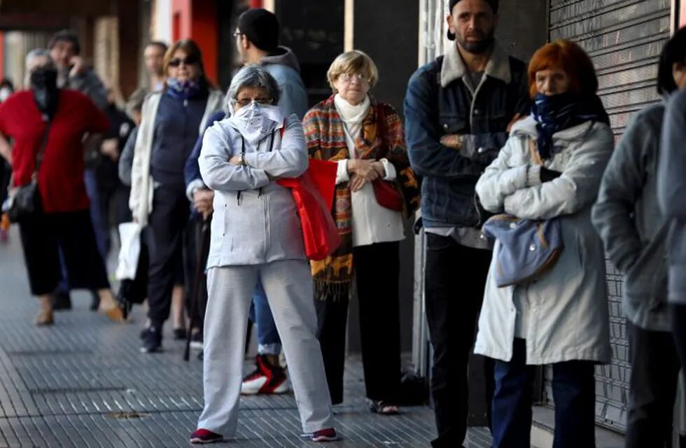 People, some wearing protective face masks, stand in line outside a bank during a government-ordered lockdown to curb the spread of the new coronavirus, in Buenos Aires, Argentina, Saturday, April 4, 2020. Banks opened for the weekend so that retirees could pick up their monthly pension payment. (AP Photo/Natacha Pisarenko)