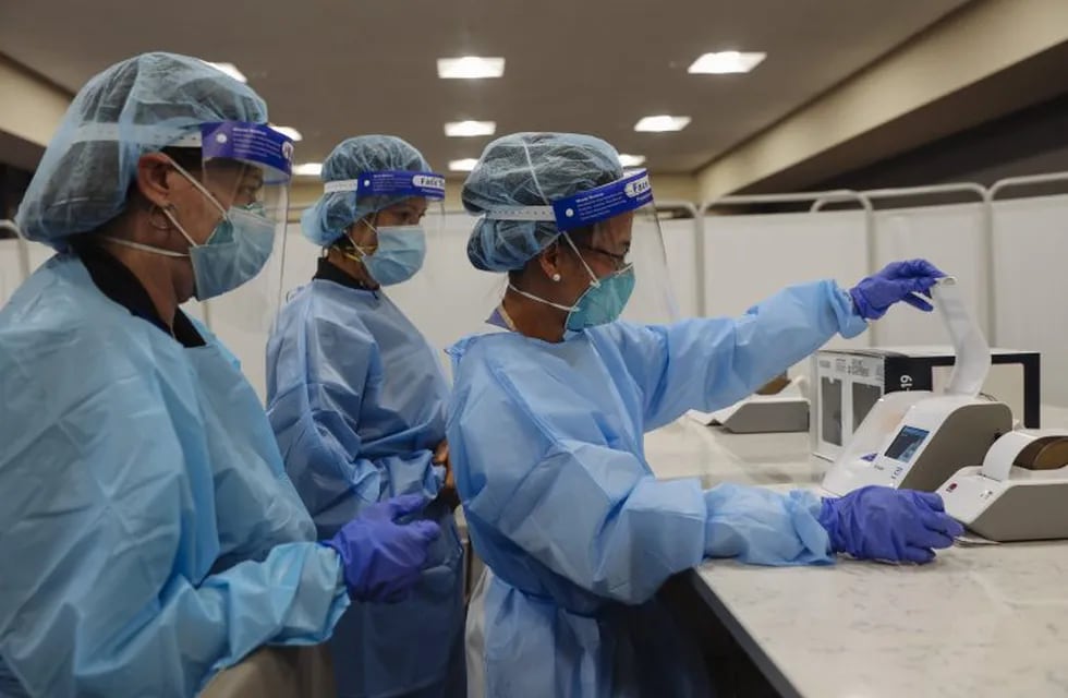 Healthcare workers wearing personal protective equipment (PPE) prepare an Abbott Laboratories ID NOW rapid test machine during a United Airlines Covid-19 test pilot program at Newark Liberty International Airport in Newark, New Jersey, U.S., on Monday, Nov. 16, 2020. From November 16 through December 11, the United Airlines will offer rapid tests to every passenger over 2 years old and crew members on board select flights from Newark Liberty International Airport to London Heathrow, free of charge. Photographer: Angus Mordant/Bloomberg
