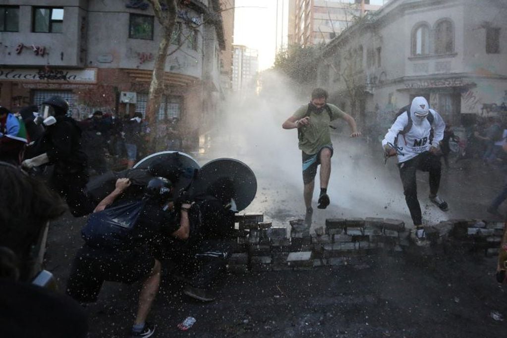 Grupos de manifestantes se enfrenta a la policía antidisturbios este lunes, durante una protesta contra el gobierno del presidente Piñera, en Santiago (Chile). EFE