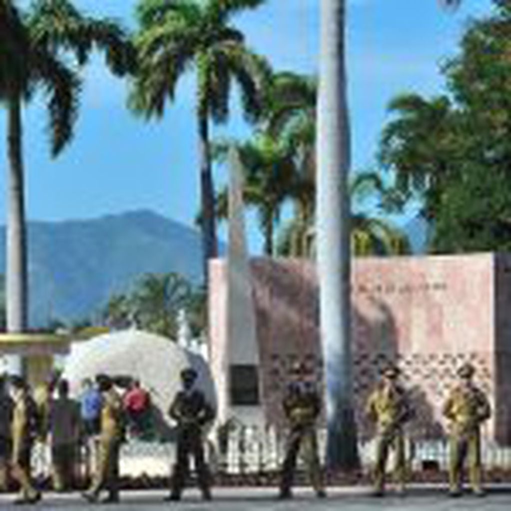 A guard of honour remains in place whilst workers fix the plaque with his name on Cuban leader Fidel Castro's tomb at the Santa Ifigenia cemetery Santiago de Cuba on December 4, 2016.
Fidel Castro's ashes were buried alongside national heroes in the cradl