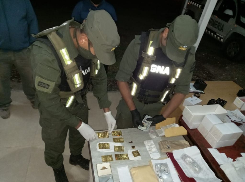 Personal de Gendarmería Nacional junto a las láminas de oro, relojes y dólares secuestrados a un conductor que viajaba a San Rafael. Gentileza Gendarmería Nacional